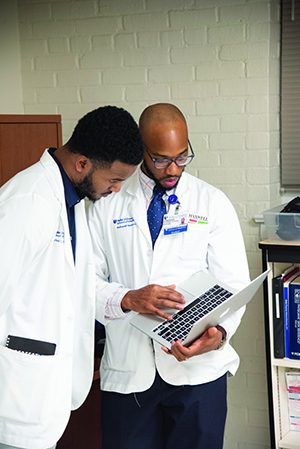 Baker and Neptune review a patient's chart before an exam.