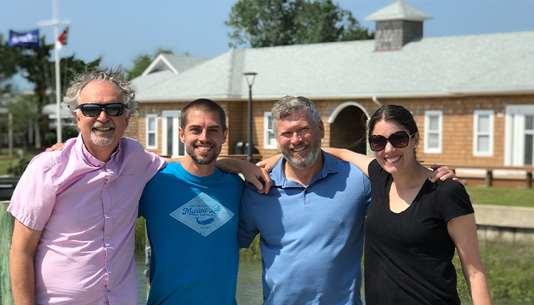 four people with arms around each other's shoulders