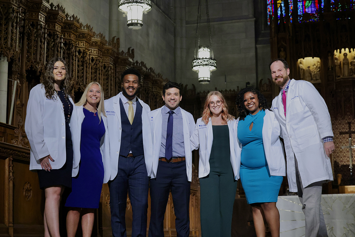 a Duke Doctor of Physical Therapy student team in their white coats with their faculty advisor