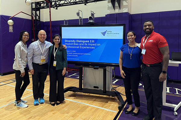 five adults standing next to a screen