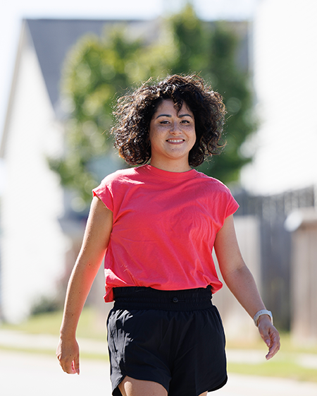 Iris Bugbee in athletic clothes, walking in her neighborhood. 