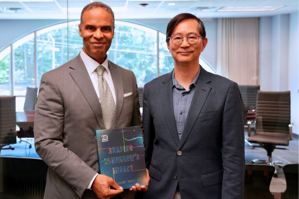 Image: In an office, Duke University Provost Alec Gallimore and Duke-NUS Dean-designate Patrick Tan pose with a book in hand.