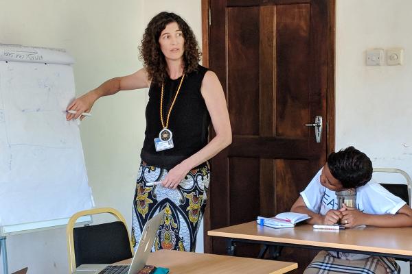 woman stands infront of classroom, student sitting at desk
